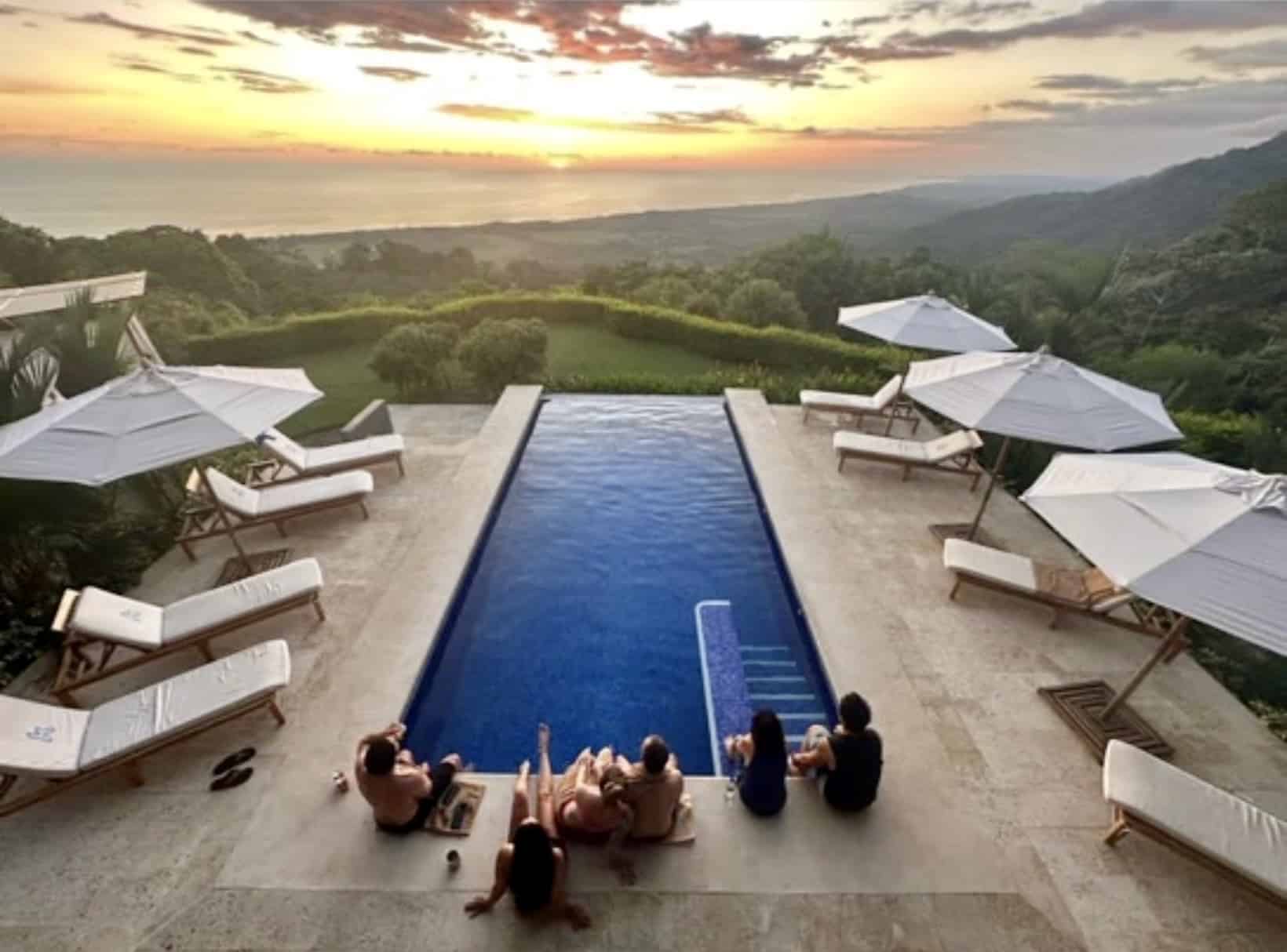 guests of kalon surf sitting around the pool overlooking the ocean during sunset