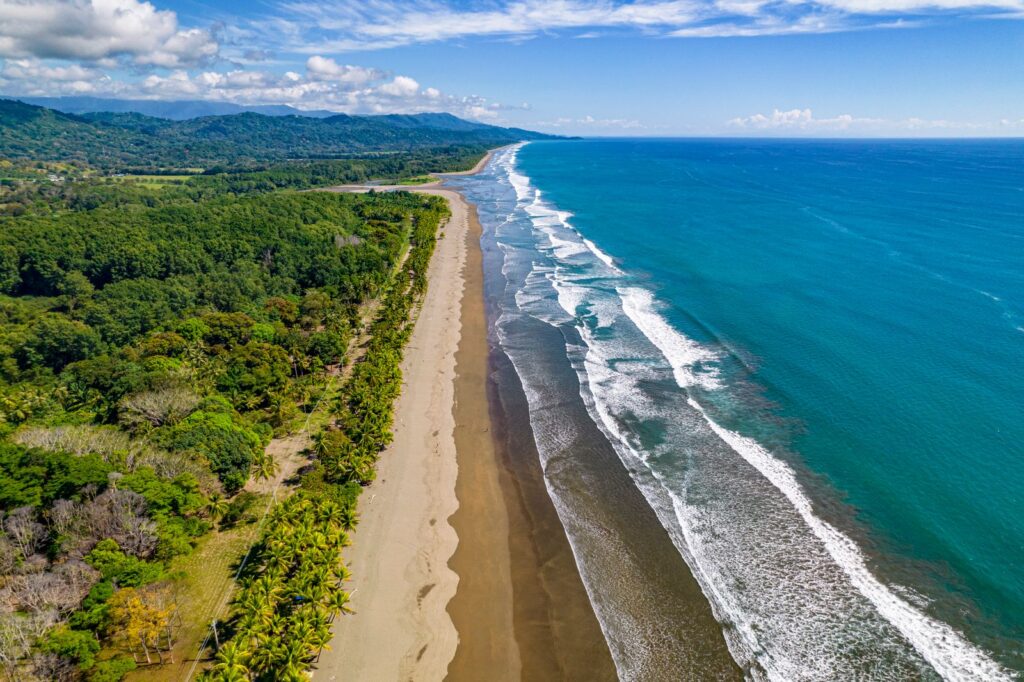 Aerial view of the jungle-backed South Pacific coast near Dominical, Costa Rica, where a river meets the sea